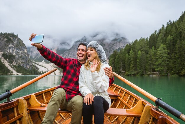 Hermosa pareja de adultos jóvenes visitando un lago alpino en Braies Italia