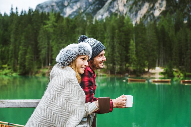 Hermosa pareja de adultos jóvenes visitando un lago alpino en Braies Italia