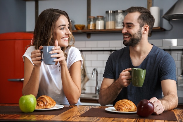 Hermosa pareja alegre desayunando en la cocina