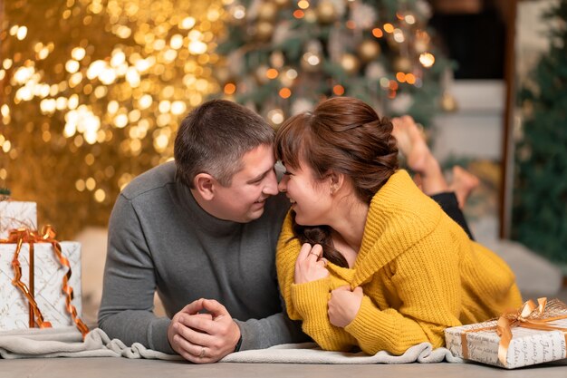 Una hermosa pareja alegre saluda las vacaciones de Navidad en un acogedor ambiente hogareño.