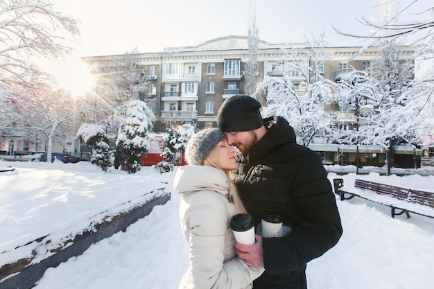 Una hermosa pareja amorosa en un parque de nieve de invierno con café