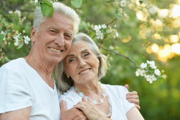 Hermosa pareja de ancianos abrazándose y posando en el parque de primavera