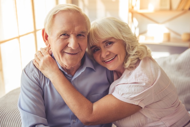 Hermosa pareja de ancianos está abrazando, mirando a cámara.