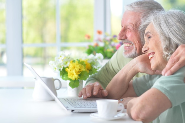 Hermosa pareja de ancianos con portátil en la mesa