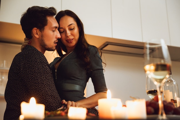 Hermosa pareja apasionada con una cena romántica a la luz de las velas en casa, besos