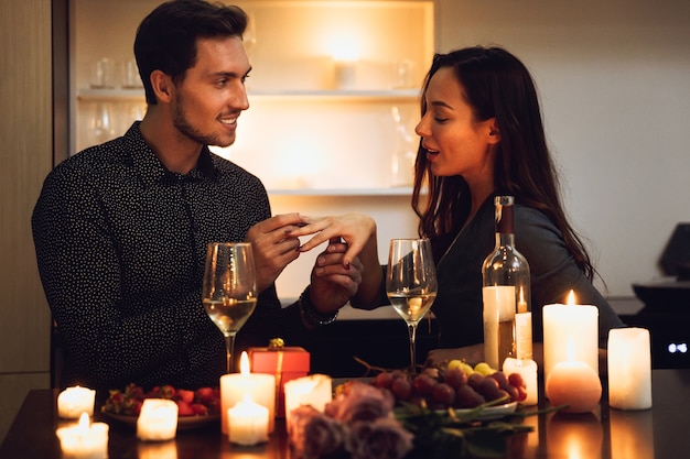 Hermosa pareja apasionada con una cena romántica a la luz de las velas en casa, hombre haciendo una propuesta