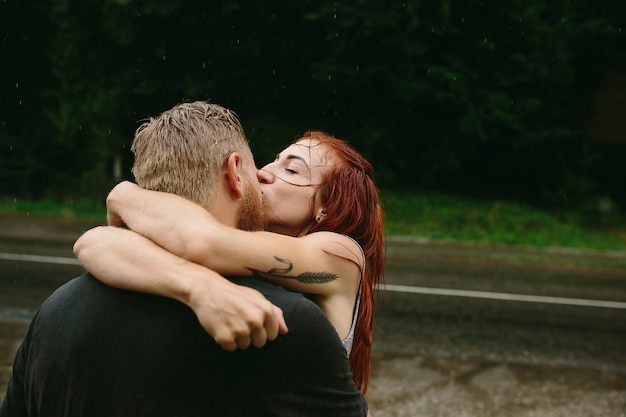 Hermosa pareja besándose afuera bajo la lluvia