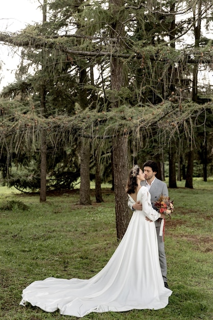 Foto hermosa pareja de bodas de recién casados abrazándose en el fondo del bosque