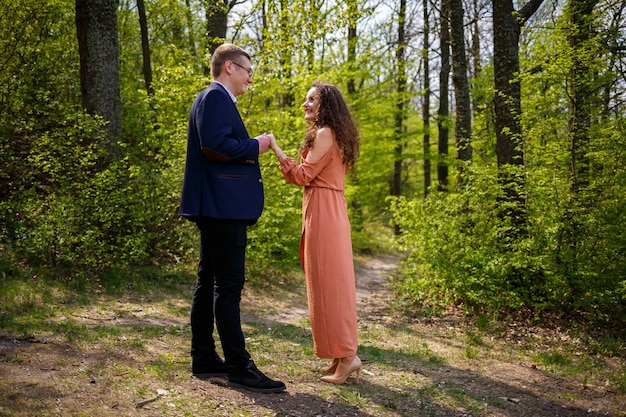 Hermosa pareja en el bosque. Chica con elegante corte de pelo abraza a su hombre en traje. Retrato de fotografía de detalles al aire libre rústico. Novio y mujer feliz