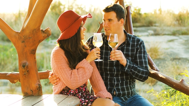 Hermosa pareja caucásica en el sol llamaradas tintineo de vasos con vino blanco.