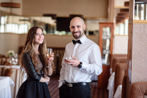 Hermosa pareja celebrando y bebiendo champán en el restaurante