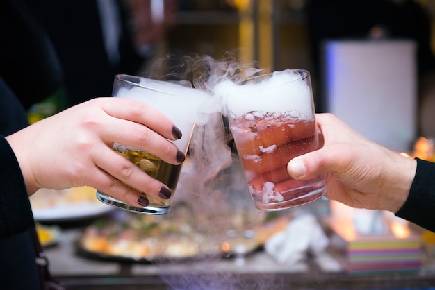 Hermosa pareja con cócteles de hielo seco en la fiesta.