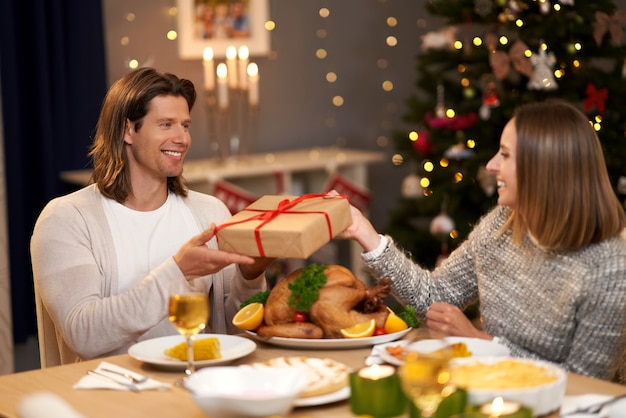 Hermosa pareja compartiendo regalos durante la cena de Navidad