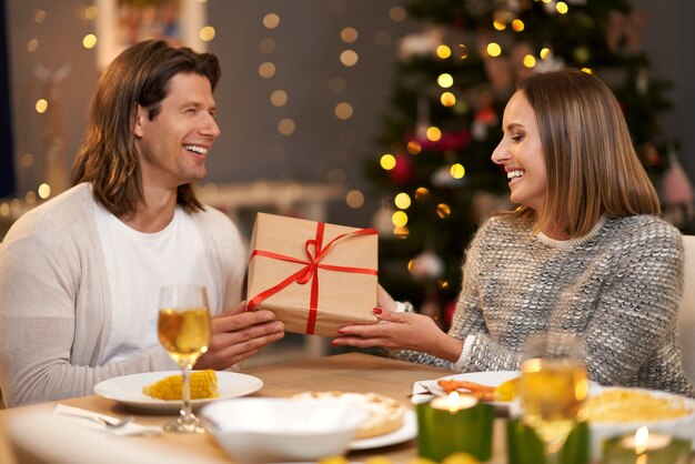 Hermosa pareja compartiendo regalos durante la cena de Navidad