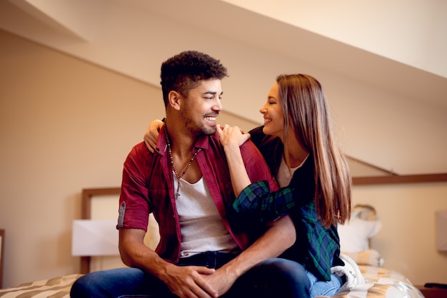 Hermosa pareja en el dormitorio, mujer abrazando a su pareja en la cama.