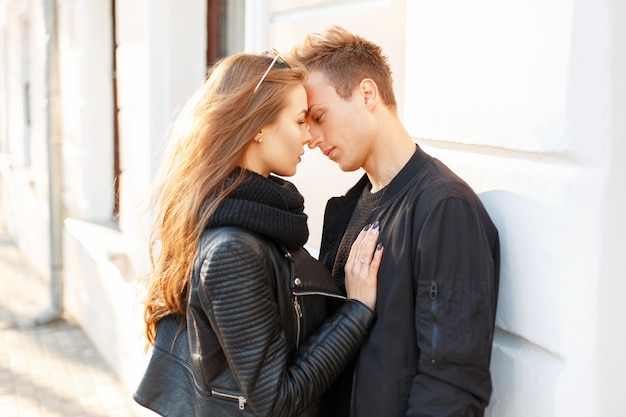 Hermosa pareja elegante de moda en ropa negra abrazándose en un día soleado