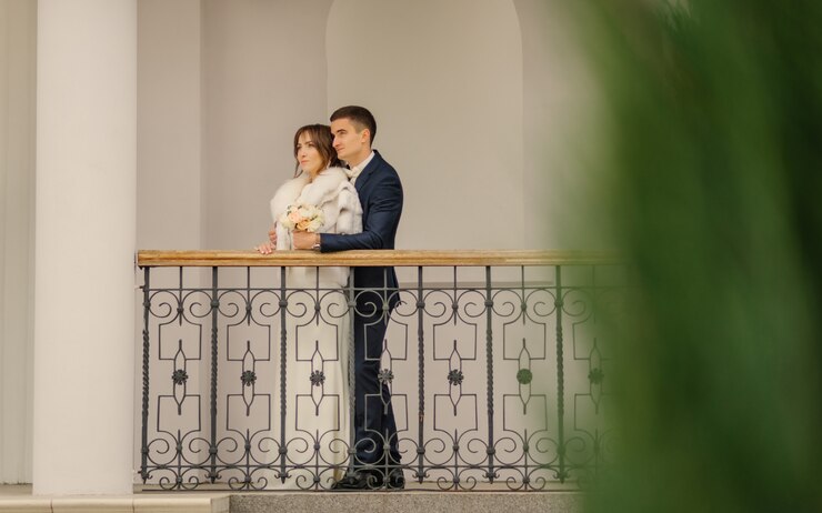 Hermosa pareja, elegante novio en traje azul y novia feliz en vestido de novia blanco posando en el día de la boda. Fotografía de bodas de recién casados con estilo.
