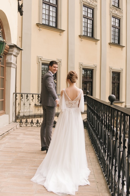 Hermosa pareja elegante de recién casados en el amor en el antiguo edificio y adoquines, boda europea