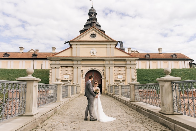 Hermosa pareja elegante de recién casados en el amor en el antiguo edificio y adoquines, boda europea