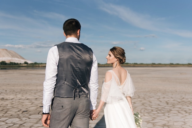 Hermosa pareja elegante de recién casados en el amor en la naturaleza montañas de sal y canteras