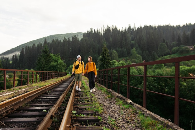 Hermosa pareja enamorada camina por el puente ferroviario con el telón de fondo de una montaña irreal