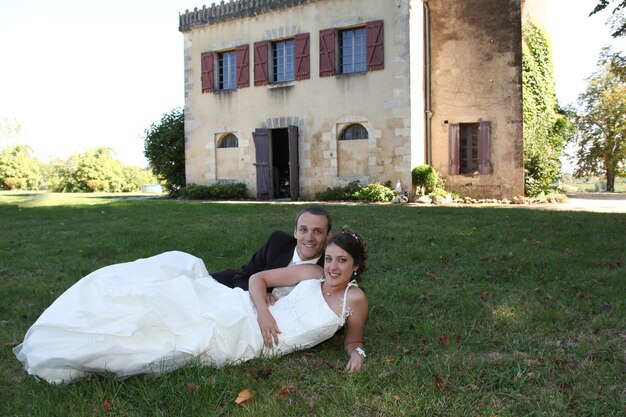 Hermosa pareja enamorada en el día de la boda tumbada en la hierba verde frente al fondo del castillo