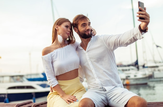 Foto una hermosa pareja enamorada se hace una selfie por teléfono en el club de yates.