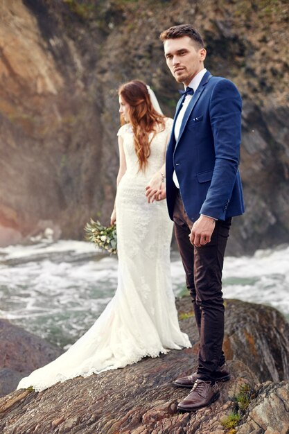 Hermosa pareja de enamorados besándose de pie en las rocas