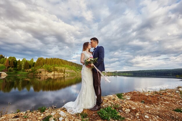 Hermosa pareja de enamorados besándose en el suelo junto al lago