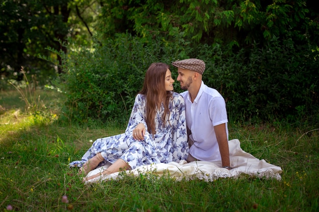 Hermosa pareja de enamorados en el picnic sonríe a la naturaleza verde