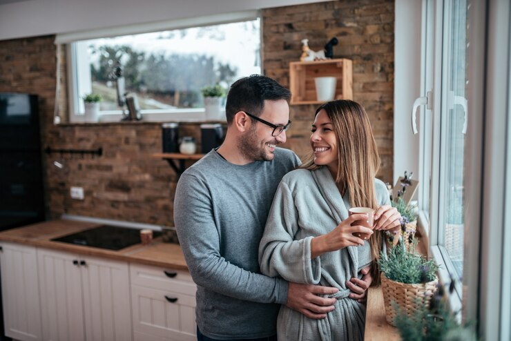 Foto hermosa pareja se está abrazando, mirándose y sonriendo mientras está de pie en la cocina.