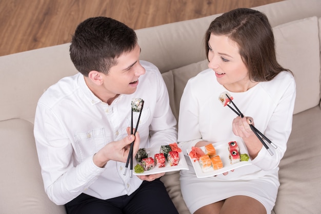 Hermosa pareja están sentados juntos en casa y comiendo.