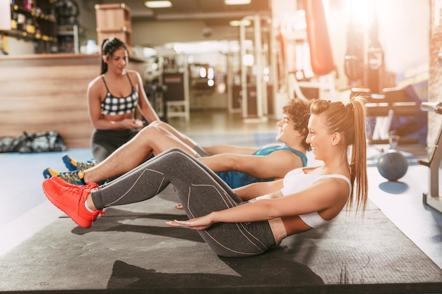 Hermosa pareja de felicidad haciendo ejercicio en el gimnasio con una entrenadora personal femenina.