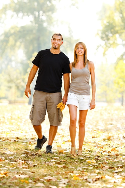 Hermosa pareja feliz tomados de la mano y caminando por el parque