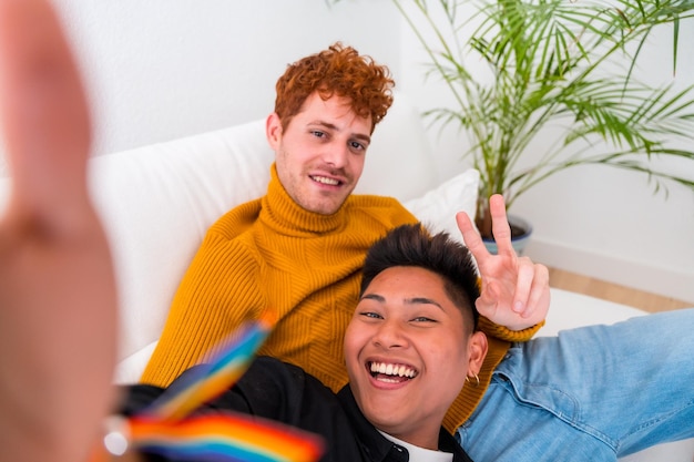 Hermosa pareja gay siendo romántica en casa en el sofá pareja gay tomando selfie concepto lgbt