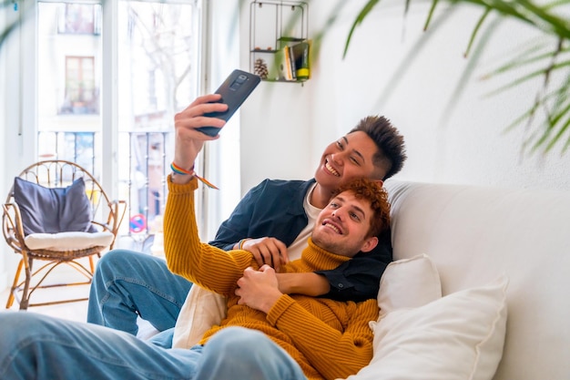 Hermosa pareja gay siendo romántica en casa en el sofá tomando un selfie concepto lgbt