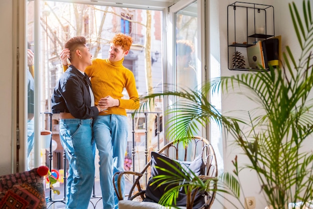 Hermosa pareja gay siendo romántica junto a la ventana abrazándose el uno al otro concepto lgbt