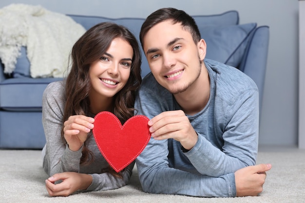 Hermosa pareja joven con corazón de fieltro en las manos