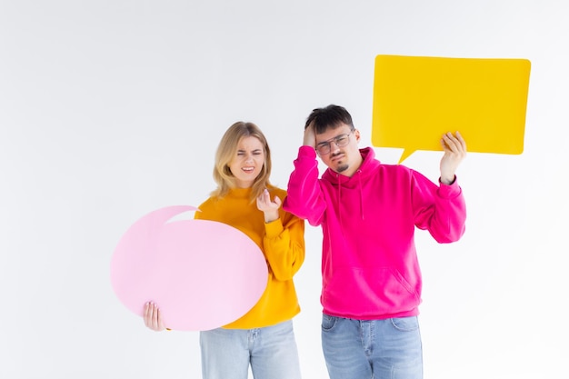 Una hermosa pareja joven con ropa informal sostiene coloridos globos de diálogo