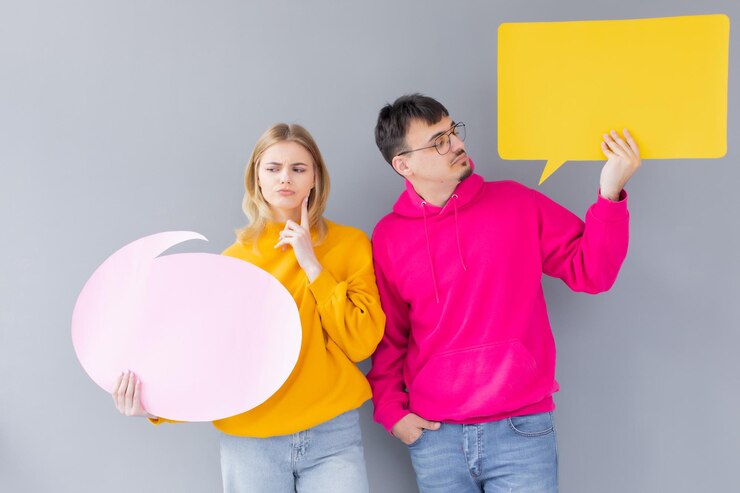 Una hermosa pareja joven con ropa informal sostiene coloridos globos de diálogo