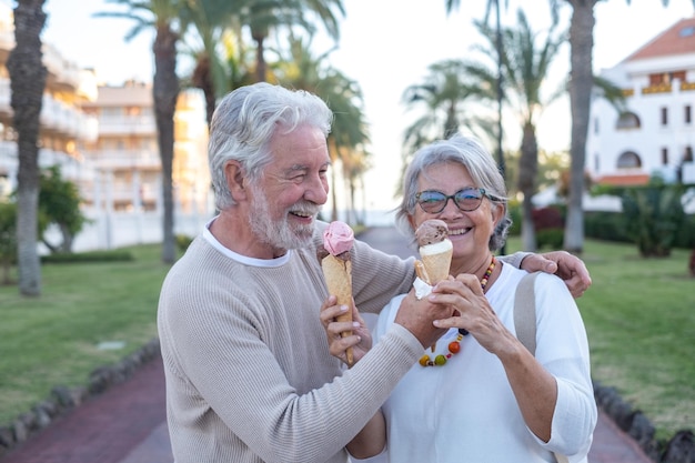 Hermosa pareja de jubilados divirtiéndose comiendo helado en el parque disfrutando de la jubilación