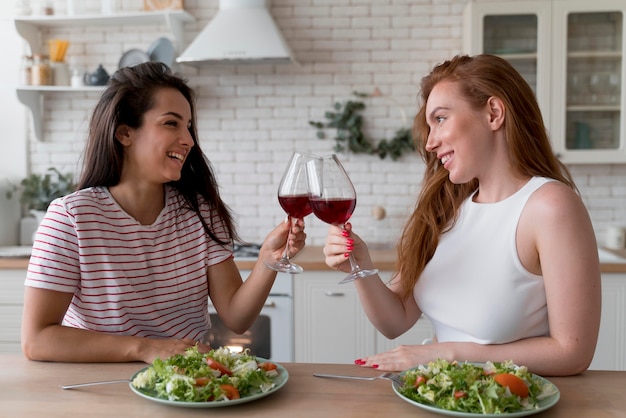 Hermosa pareja de lesbianas animando con unas copas de vino