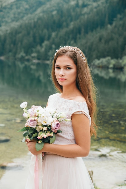 Hermosa pareja moderna cerca de un lago en las montañas hacen fotos de boda