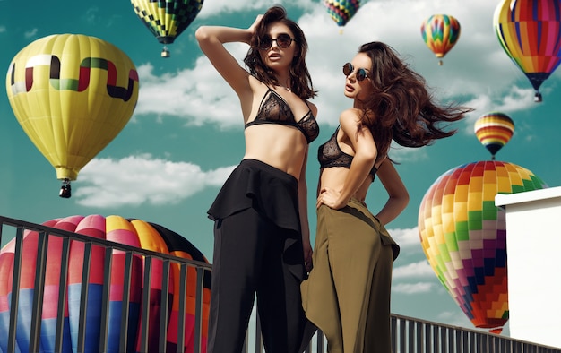 Hermosa pareja de mujeres en sujetador contra el fondo de globos aerostáticos