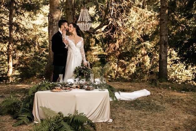 Hermosa pareja de novios abrazándose en el fondo del bosque.