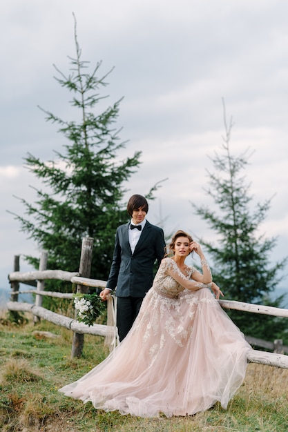 Hermosa pareja de novios besándose y abrazándose cerca de la orilla de un río de montaña con piedras