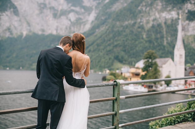 Una hermosa pareja de novios camina sobre una antigua catedral de fondo en una ciudad austriaca de hadas