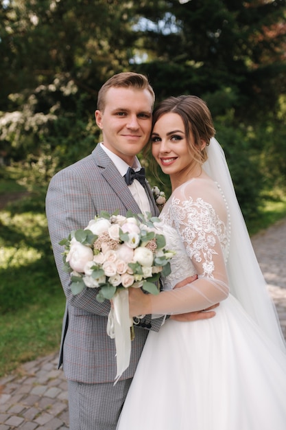 Hermosa pareja de novios en el día de la boda caminando al aire libre. Novia joven atractiva con