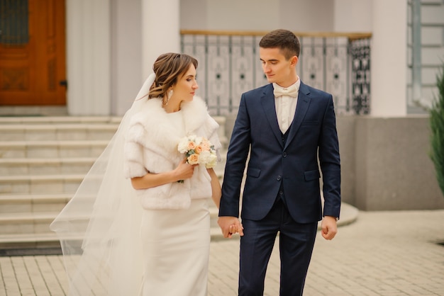 Hermosa pareja de novios. Novia y el novio en el día de la boda caminando al aire libre. Novios, recién casados felices.