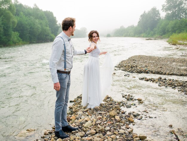 Hermosa pareja de novios de pie cerca de la montaña con vista perfecta